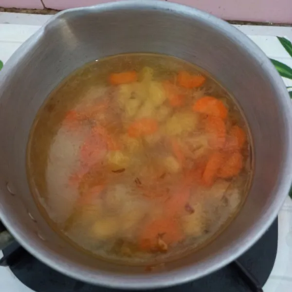 Masukkan kentang dan wortel, masak hingga agak empuk, kemudian tambahkan air, tunggu sampai mendidih dan sayuran matang.