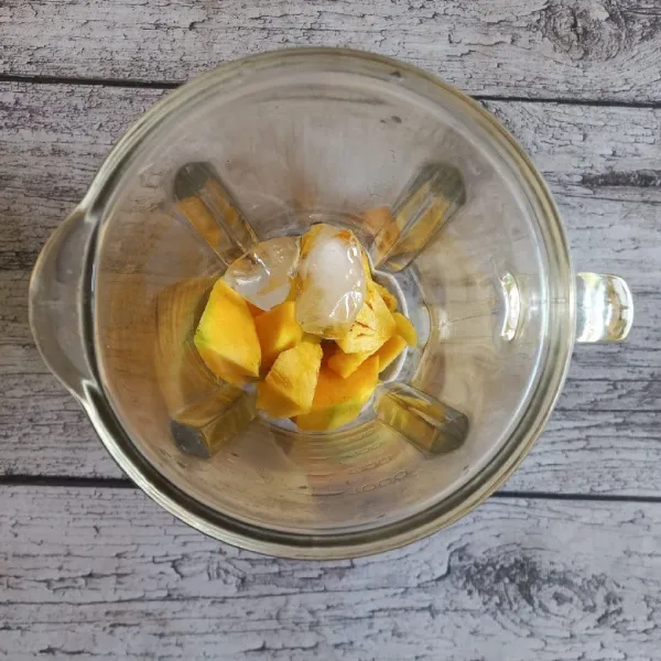 Madu buah mangga, nanas dan es batu ke dalam gelas.