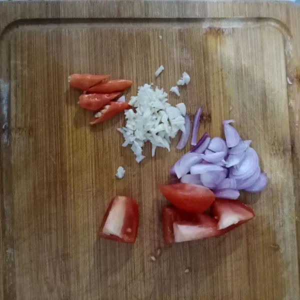Rajang halus bawang. Potong-potong cabai dan tomat.