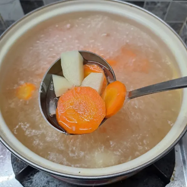 Rebus air sampai mendidih, masukkan bumbu halus, wortel, dan kentang. Masak sampai ½ matang.