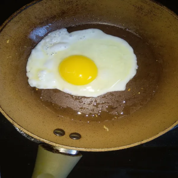 Dengan minyak sisa menggoreng bawang tadi, goreng telur ceplok dengan api kecil. Saya buat setengah matang.