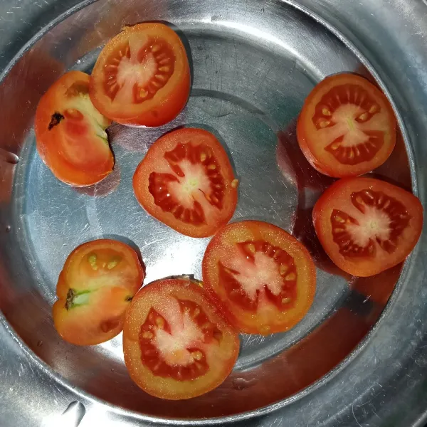Cuci bersih tomat lalu belah menjadi dua.