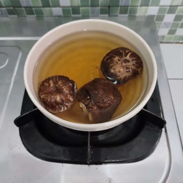 Rendam jamur shiitake dengan air panas hingga mengembang dan empuk, kemudian bilas hingga airnya jernih. Setelah itu potong-potong