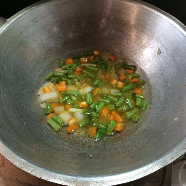 Kemudian tumis bawang putih dan bawang bombay sampai harum. Lalu masukkan wortel, buncis dan air. Biarkan sampai empuk.