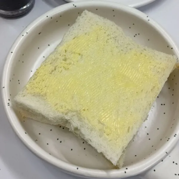 Oles margarin di lapisan roti paling atas.