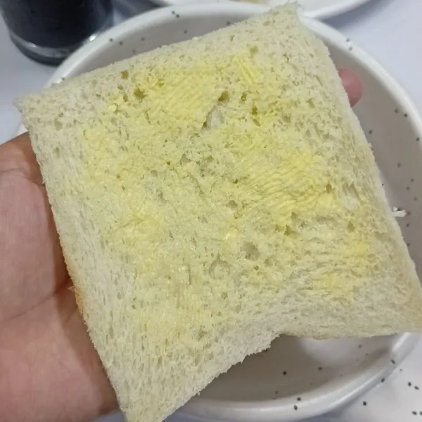 Oles 1 sisi roti dengan margarin. Letakkan sisi ini di bawah.