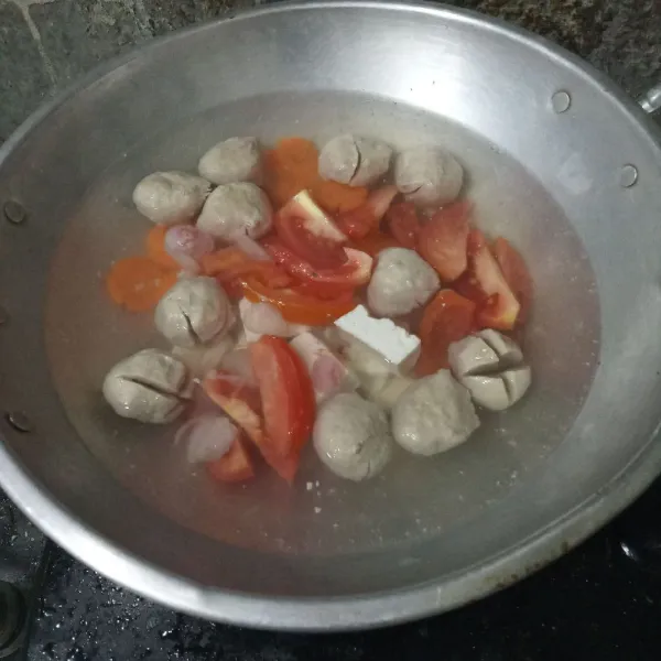 Tambahkan tomat, tahu, garam, lada dan kaldu bubuk. Masak hingga wortel empuk.