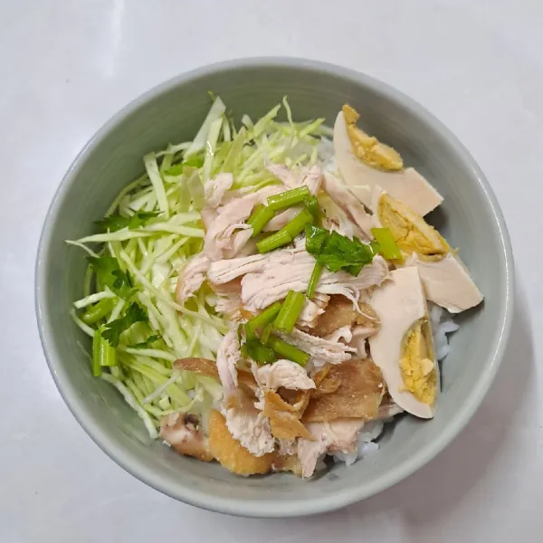 Ambil mangkok, beri nasi, irisan kubis, ayam suwir dan irisan telur rebus. Lalu tuang kuah secukupnya. Beri sambal. Sajikan.