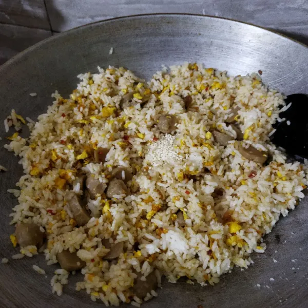 Masukan nasi, aduk dan tambahkan garam serta kaldu jamur, lanjutkan mengaduk nasi goreng dengan api sedang sampai semua bahan menyatu. Koreksi rasa.