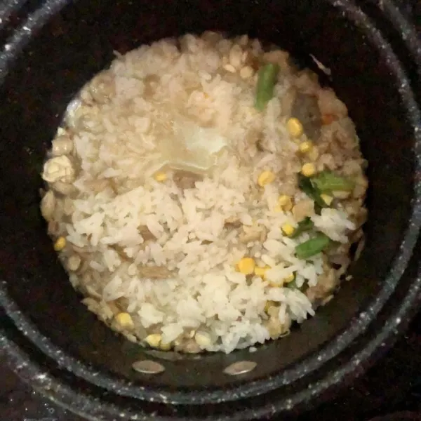 Masukkan nasi, tambahkan air lalu masak hingga menjadi bubur masukkan buncis, jagung, daun pre dan seledri. Aduk hingga matang.