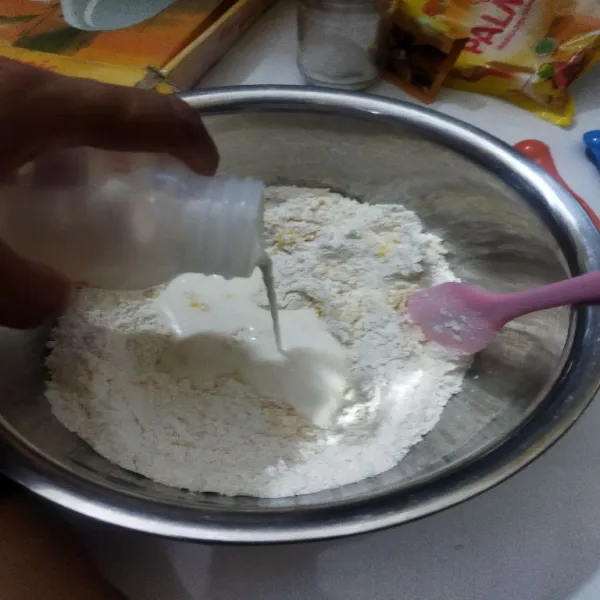 Tuangi susu cair perlahan sambil di aduk sampai adonan tidak kering dan lembab.