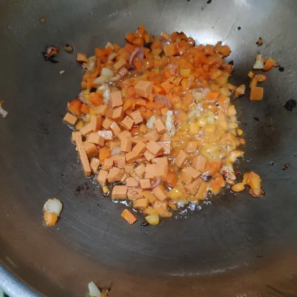 Tumis bawang putih dan bawang merah yang sudah dicincang halus. Lalu masukan wortel yang sudah dipotong dadu kecil dan sosis. Aduk rata.