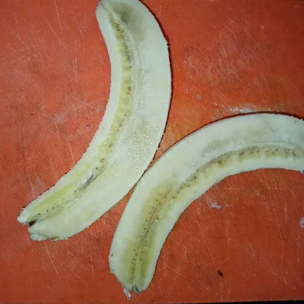 Kupas pisang kemudian belah pisang menjadi dua.