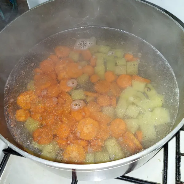 Didihkan air dan kaldu, masukkan kentang dan wortel.