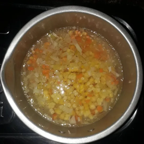 Tambahkan air, masak hingga mendidih. Masukkan jagung manis dan wortel. Masak selama 5 menit atau sampai matang.