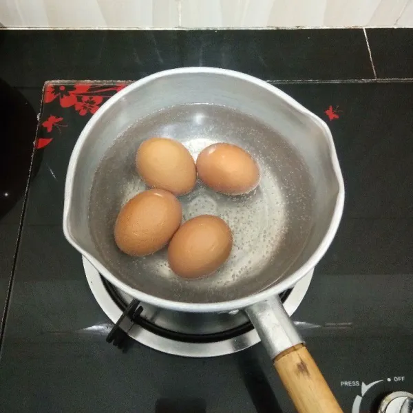 Rebus telur hingga matang, lalu kupas dan sisihkan.