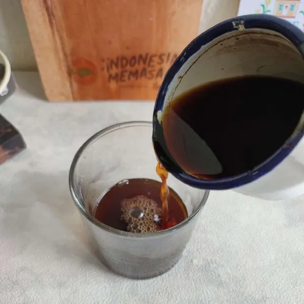 Pindahkan kopi ke dalam gelas saji yang lebih besar, ampas jangan ikut dituang.