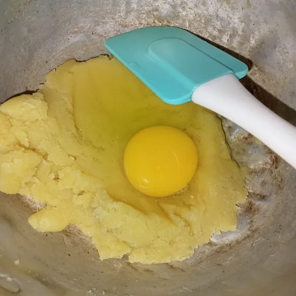 Masukkan tepung, aduk cepat hingga berbentuk adonan matikan api. Tunggu hangat lalu masukkan telur, aduk rata.