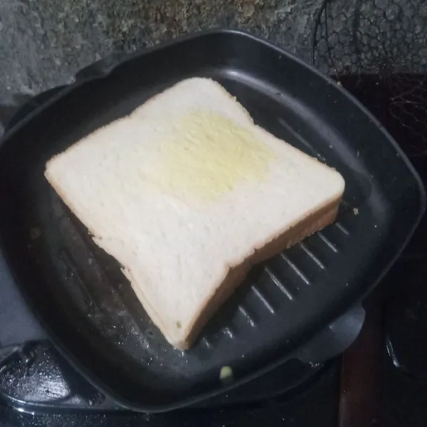 Oles grill pan dengan margarin, letakkan roti diatasnya.