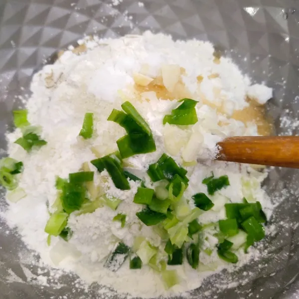 Kemudian masukkan tepung terigu dan tepung tapioka dan bawang prei, aduk hingga rata.