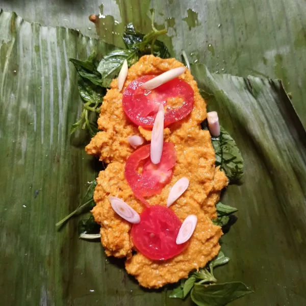 Tata kemangi di dasar daun pisang, beri daun salam, bumbu, beri tomat lalu potongan serai.