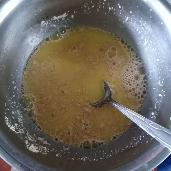 Dalam wadah, masukkan kuning telur dan air, kocok rata. Kemudian masukkan gula pasir dan ragi instan. Aduk sampai tercampur rata.