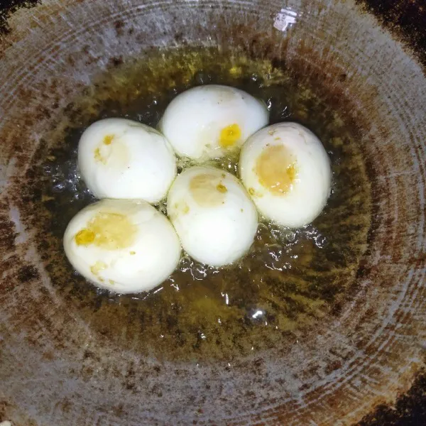 Rebus telur, kupas lalu goreng telur hingga berkulit.
