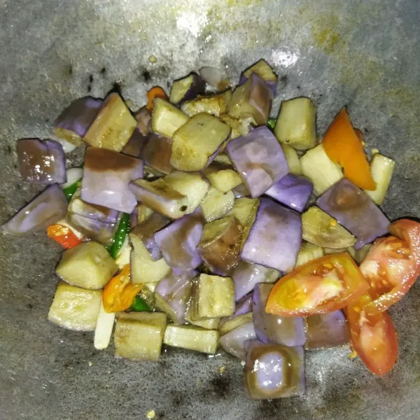 Masukkan terong ungu goreng, garam, kaldu bubuk, gula pasir, dan tomat.