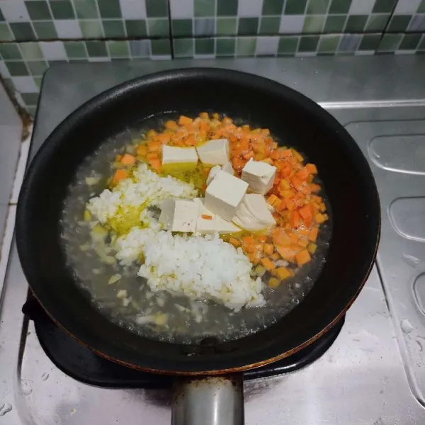Lalu masukkan nasi, tahu, dan wortel. Masak dengan api kecil sambil ditutup.