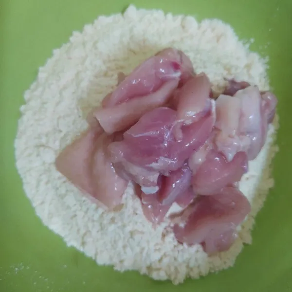 Masukan ayam ke dalam mangkok berisi tepung lalu baluri hingga merata.