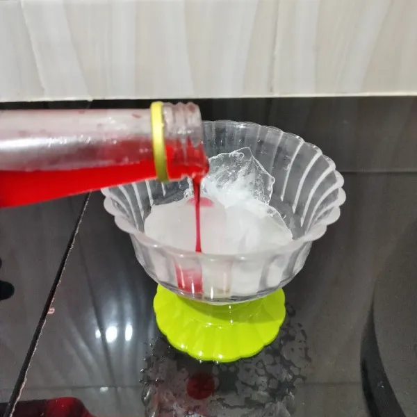 Masukkan es batu ke dalam gelas. Lalu tambahkan sirup cocopandan.