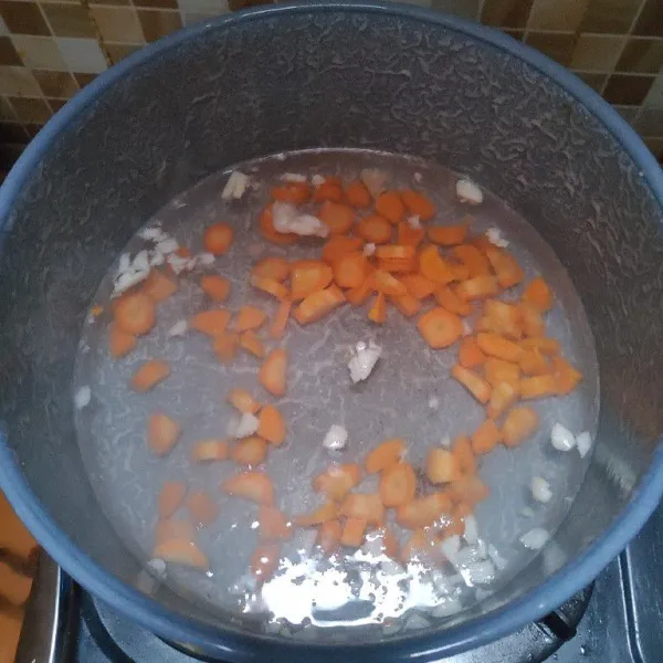 Didihkan air, masukkan bawang putih cincang, masak hingga kuah mendidih kemudian masukkan wortel yang sudah dipotong kecil-kecil.