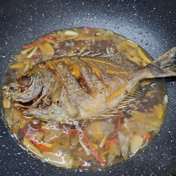 Masukkan ikan goreng, siram-siram dengan tumisan. Balik ikan, biarkan bumbu meresap.