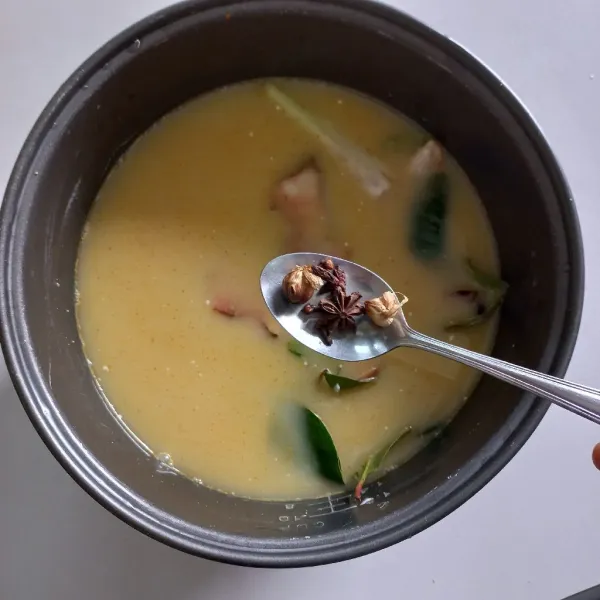 Tambahkan kapulaga, bunga lawang dan cengkeh, nyalakan magic com, masak nasi hingga matang.