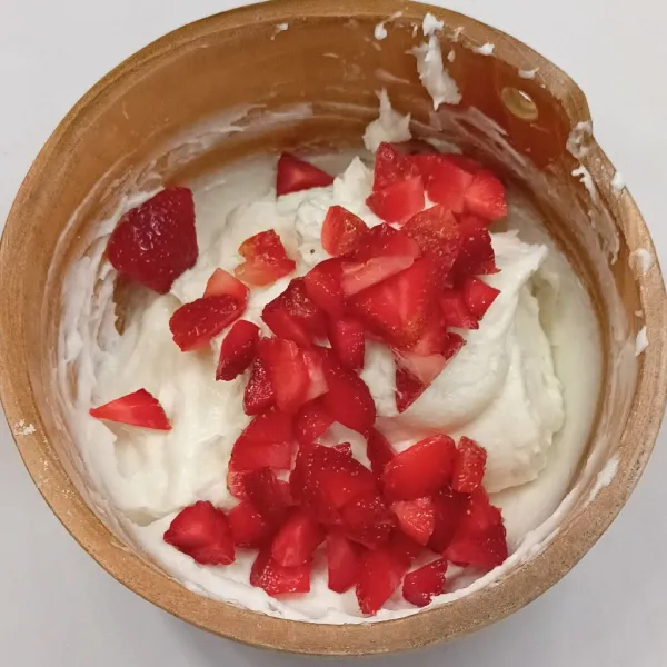 Kocok whipped cream, air es, beri potongan strawberry.