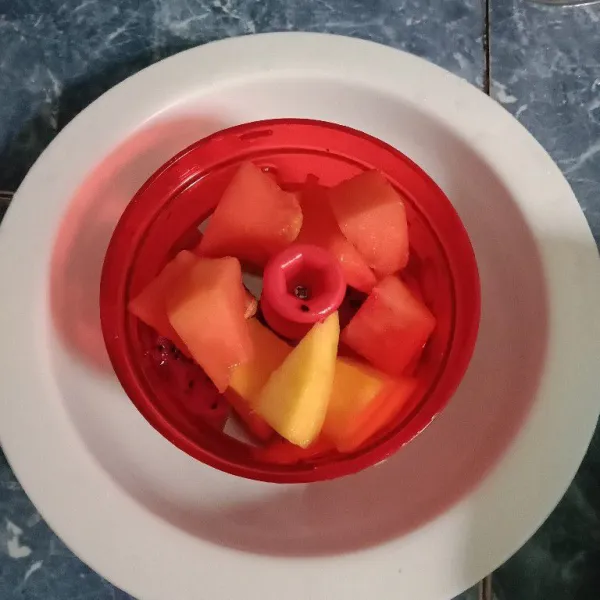 Masukkan buah dan air es ke dalam blender.