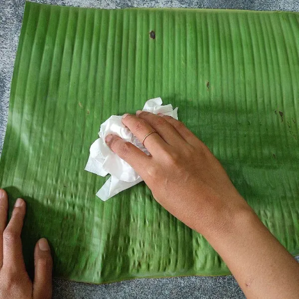 Panaskan sebentar daun pisang di atas kompor agar layu kemudian lap hingga bersih. Potong-potong daun sebesar 4 jari tangan.