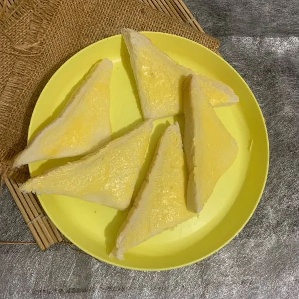 Olesi roti tawar dengan mentega atau butter di sisi atasnya.