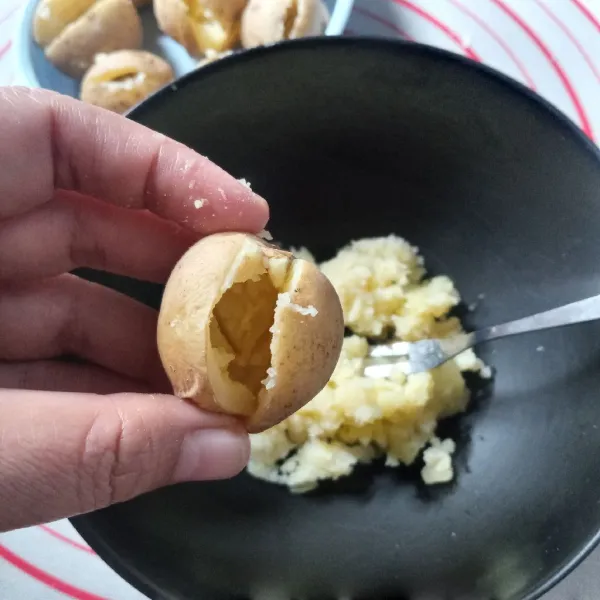 Setelah tidak terlalu panas, belah kentang tidak putus lalu kerok dagingnya dan tampung dalam mangkok.