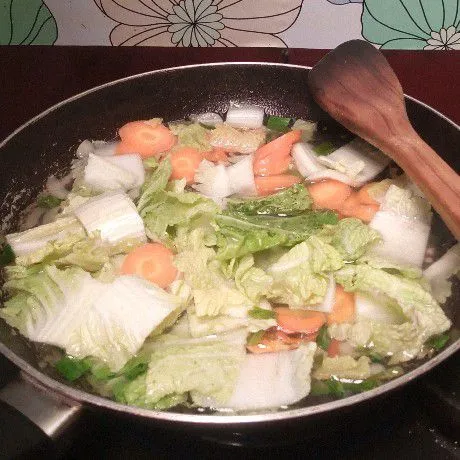 Selanjutnya tuang secukupnya air, masukkan wortel dan sawi. Aduk. Masak sampai wortel setengah matang.