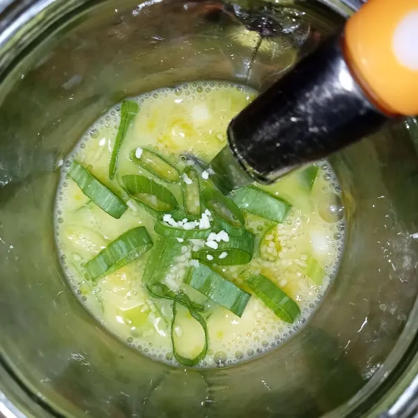 Pecahkan telur di dalam gelas lalu masukkan irisan bawang prei, tambahkan lada, garam dan kaldu jamur.