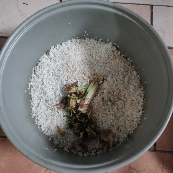 Masukkan tumisan bawang dan daun jeruk ke dalam panci magic com yg sudah di isi beras.