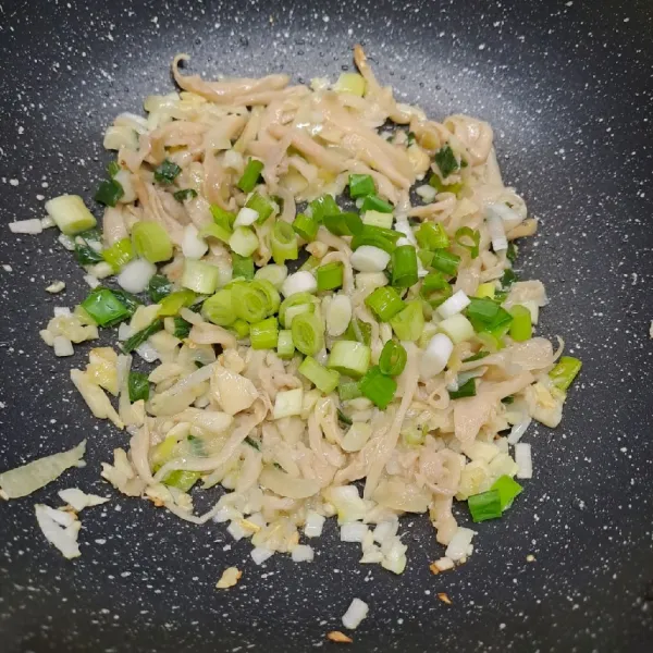Masukkan jamur tiram dan irisan daun bawang, tumis sampai daun bawang layu.