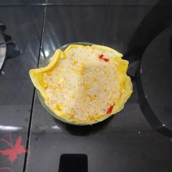 Lalu isi dengan nasi goreng hingga penuh dan rapatkan pinggiran telur dadar.