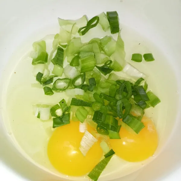 Pecahkan telur ke dalam mangkuk lalu masukkan bawang prei yang sudah dipotong.