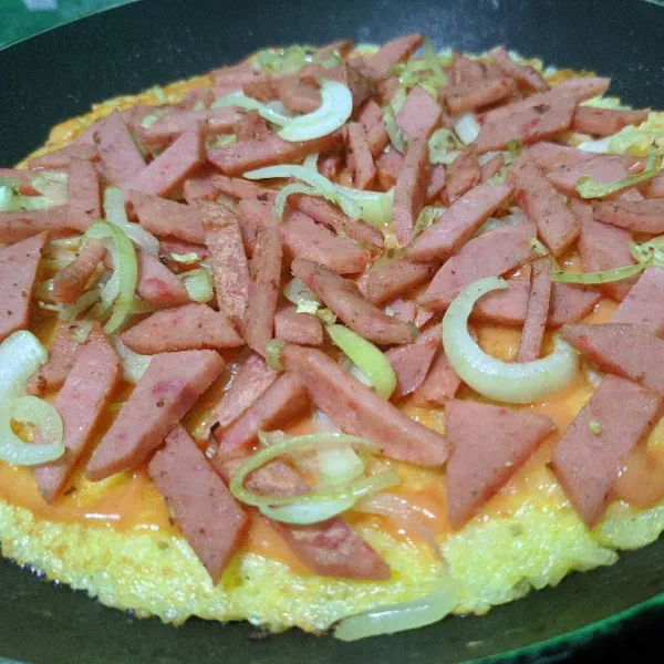 Olesi bagian atas pizza dengan campuran saos dan mayonaise, ratakan dengan sendok, setelah rata beri tumisan sosis dan bawang bombay, ratakan kembali.