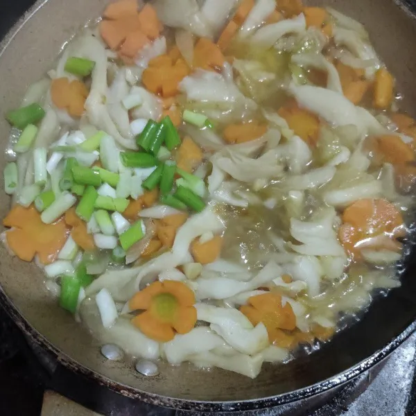 Masukkan irisan daun bawang, gula, garam, minyak wijen, dan lada bubuk aduk rata masak hingga jamur layu kemudian koreksi rasa, angkat dan sajikan.