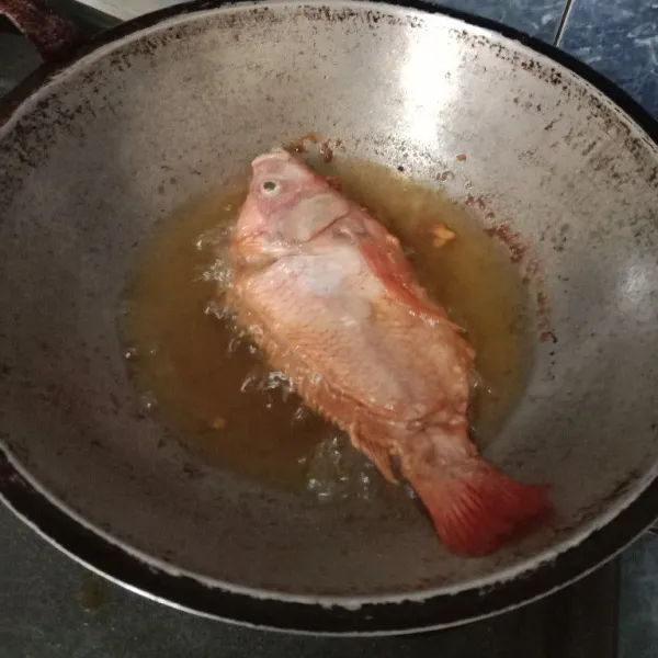 Panaskan minyak dalam wajan. Lalu goreng ikan dalam minyak panas.