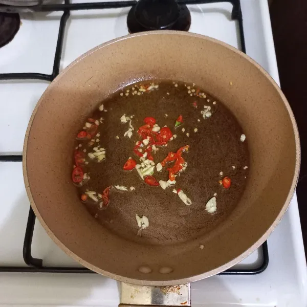 Panaskan minyak, goreng dengan api kecil irisan cabe rawit dan bawang putih cincang hingga kecokelatan.