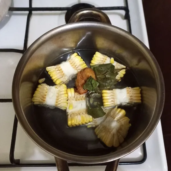 Didihkan air dalam panci, masukkan potongan jagung manis, lengkuas dan daun salam.